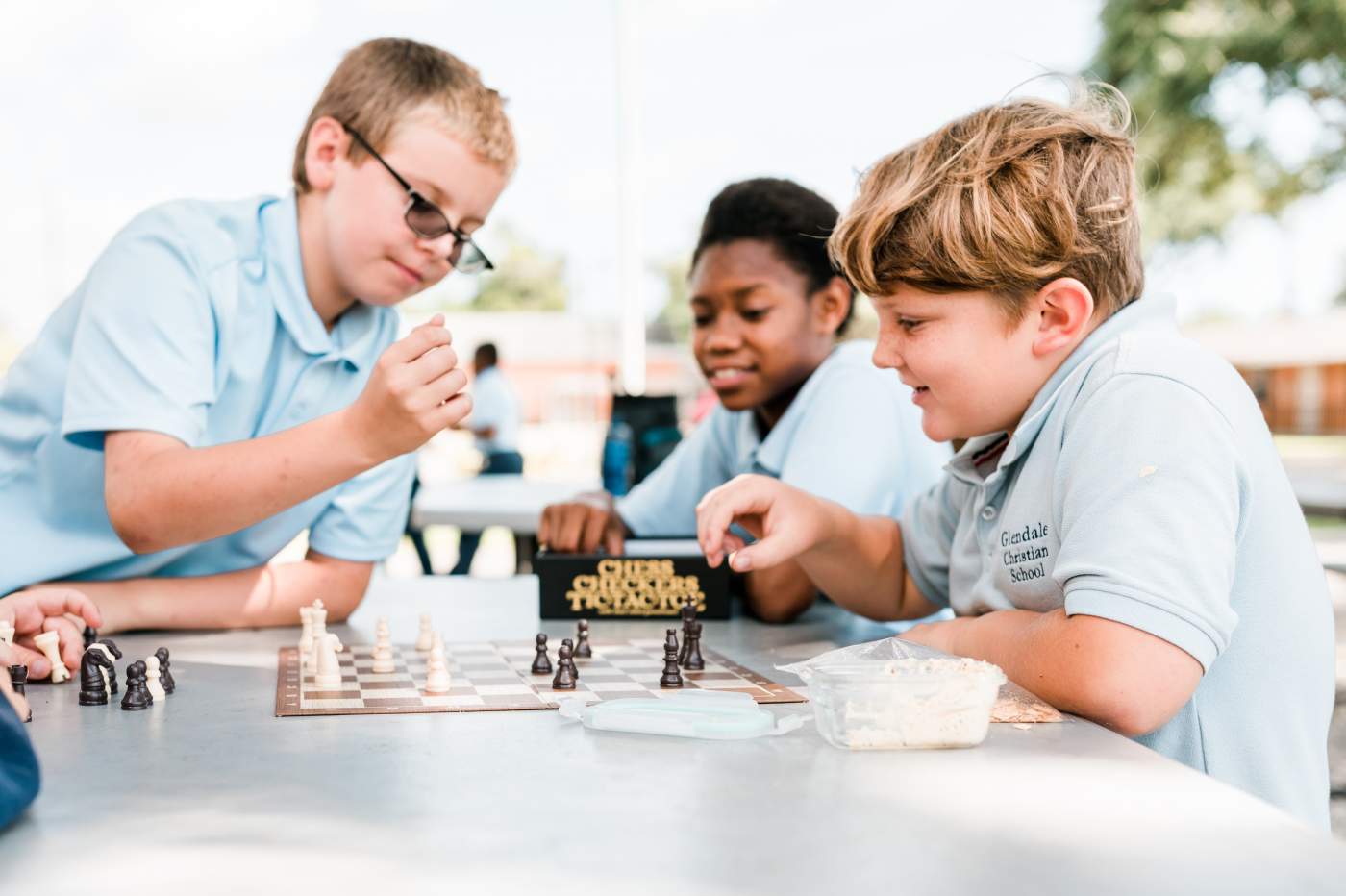 Three young boys playing chess