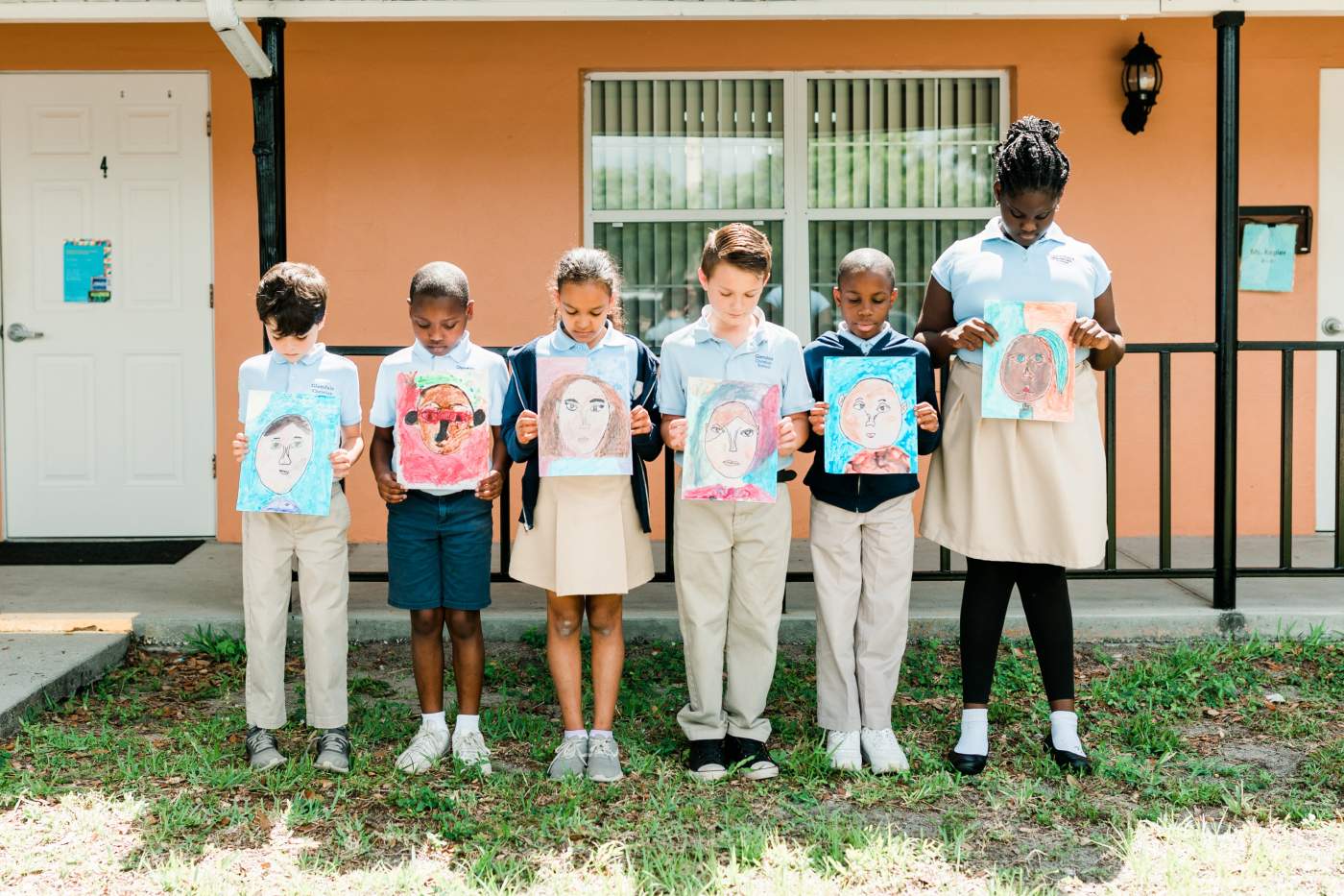6 kids holding up their drawings outside