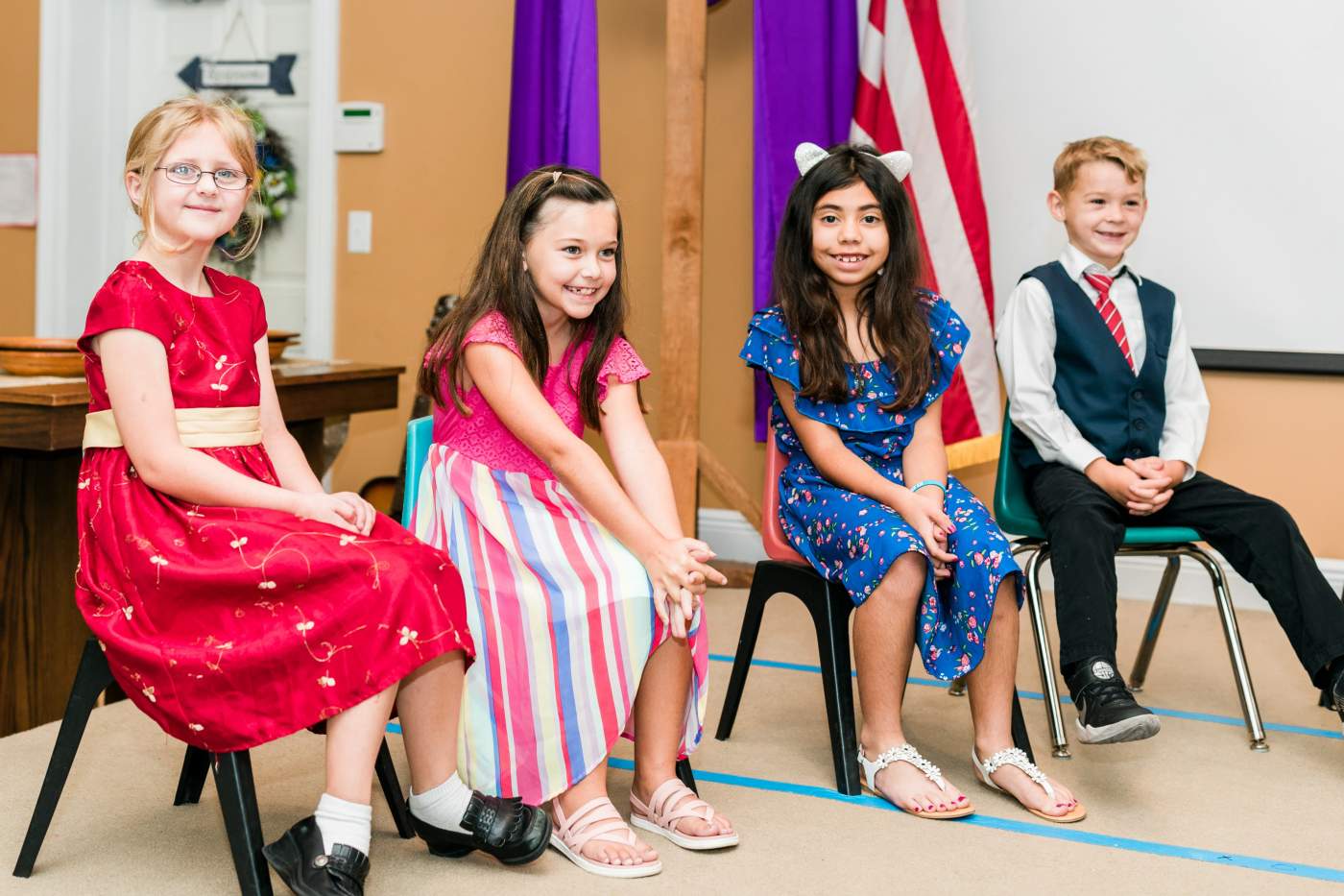 One young man and three young ladies sitting and smiling